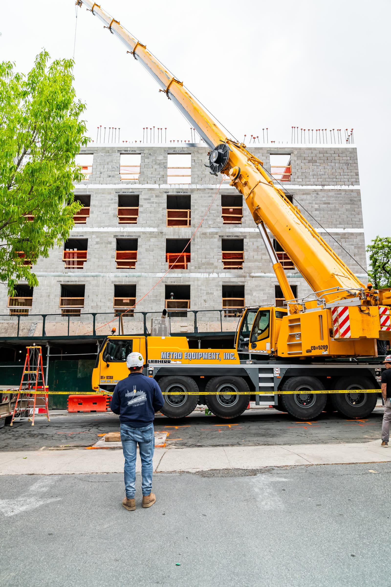 Metro Erectors crew member in a company hoodie watching the crane boom over a jobsite