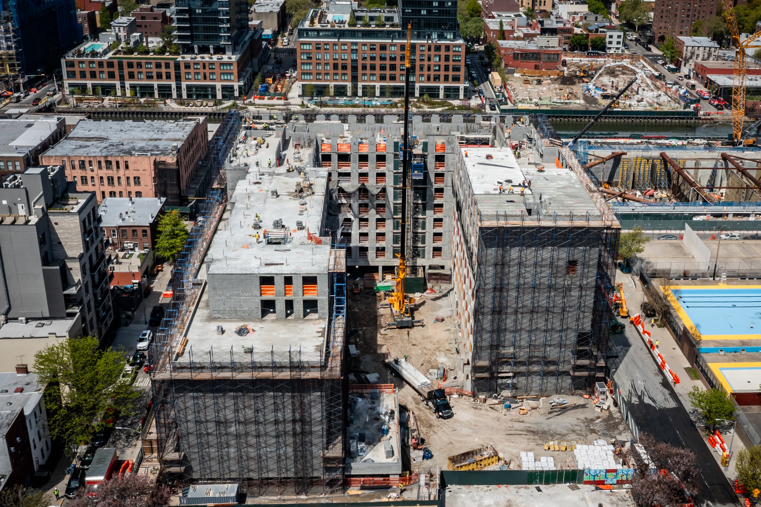 Top-down aerial of a full-block jobsite with two buildings and a crane between them