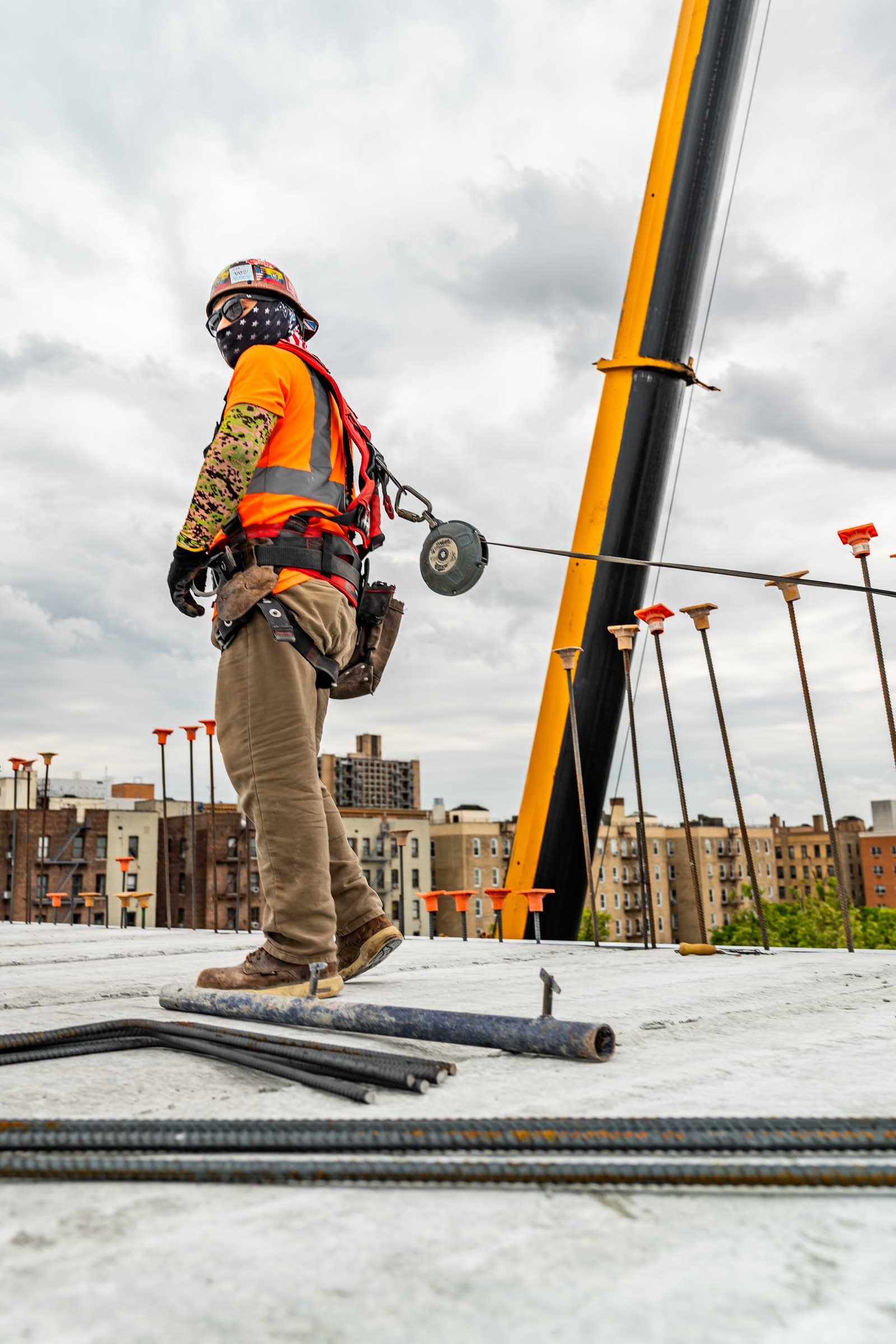 Harnessed ironworker on a deck with a crane boom behind