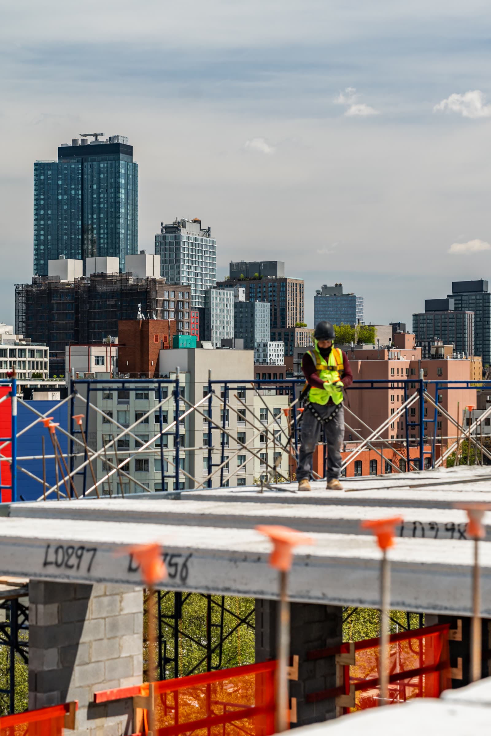 Metro Erectors crew member at a plank edge with the city skyline behind